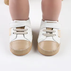 Close-up of white and tan baby walking shoes with hook-and-loop strap and elastic laces