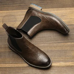 Detailed view of brown retro brogue Chelsea boots with carved patterns on wood background