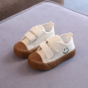 Beigefarbene Kinder-Stoffschuhe mit Smiley und brauner strukturierter Kekssohle.