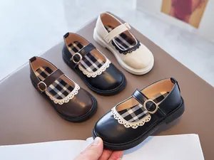 Detailed close-up of girls' black Mary Jane shoes with scalloped lace and plaid lining.