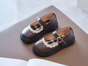 Detail view of brown girls Mary Jane shoes with white lace trim and plaid lining
