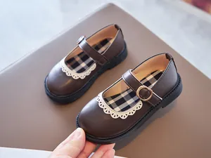 Close-up of girls brown Mary Jane shoes with white scalloped lace trim and buckle.