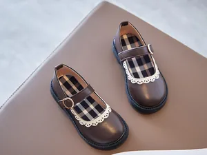 Detail of girls' brown Mary Jane leather shoes with white lace trim and plaid insole.
