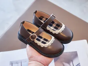 Close-up of brown girls' Mary Jane leather shoes with white lace trim and buckle.