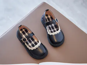 Detailed view of girls' black Mary Jane shoes with white lace trim and checkered insole