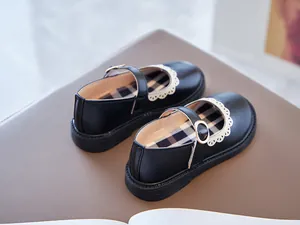 Close-up detail of girls black leather Mary Jane shoes with elegant white lace trim