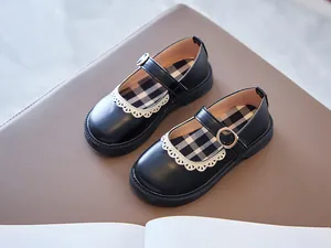 Close-up of classic black Mary Jane shoes for girls featuring white lace trim and gold buckles