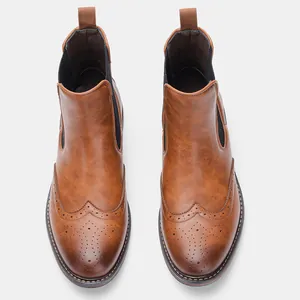Detailed top view of vintage brown leather Chelsea boots featuring classic brogue wingtip patterns.