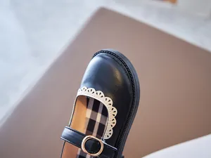Detailed close-up of girls Mary Jane leather shoes with white lace trim and gold buckle