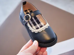 Close-up of black Mary Jane girls' shoes with white lace trim and checkered lining