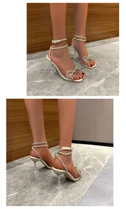 Close-up detail of elegant square toe sandals with rhinestone bow and glass heel
