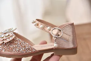 Detailopname van fonkelende prinsessenschoenen met parelbandje en strik van strass