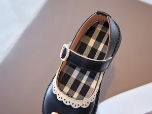 Close-up detail of black girls Mary Jane leather shoe with lace trim and plaid lining