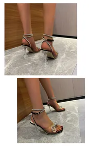 Detailed view of square toe sandals with rhinestone bow and clear wine glass heel