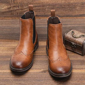 Vintage brown men's Chelsea boots with decorative wingtip brogue detailing on wood.