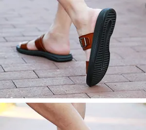 Close-up of men's brown leather beach sandals with adjustable buckles on a brick path.
