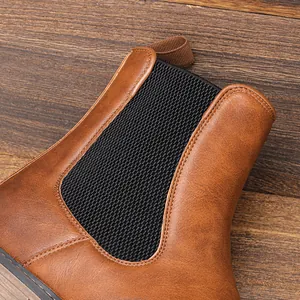 Detailed view of brown men's Chelsea boot leather texture and black elastic side panel