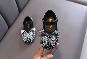 Primer plano de zapatos de princesa negros para niñas con gran mariposa de pedrería