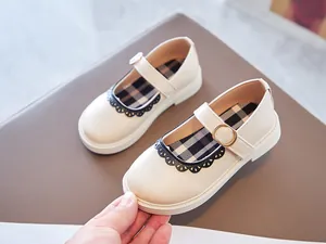 Close-up of cream girls' Mary Jane shoes with black lace trim and check insole
