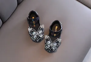 Primer plano del detalle de mariposa de strass brillante en zapatos de niña