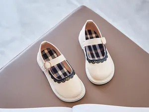 Overhead view of cream girls' Mary Jane shoes with black scalloped lace trim detail