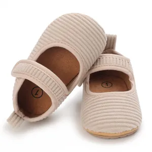 Détail de chaussures de marche pour bébé en velours côtelé doux beige avec bride.