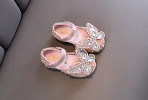 Primer plano de zapatos de princesa rosas para niñas con mariposa de diamantes y perlas