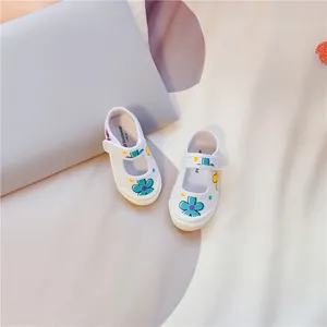 Draufsicht auf weiße Kinder-Stoffschuhe mit bunten Blumenprints und Klettverschlussriemen