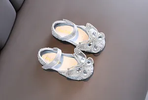 Detalle de zapatos de princesa plateados para niña con lazo de mariposa de diamantes imitación