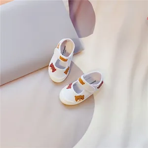 Detail der weißen Leinwandschuhe für Kleinkinder mit süßem Bärenprint und Klettverschluss