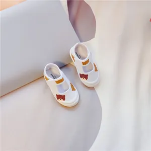 Detailansicht weißer Kleinkind-Leinenschuhe mit süßem Bärenmuster und Klettverschluss.