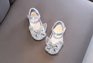 Detalle de zapatos de princesa plateados para niña con decoración de mariposa en strass brillante