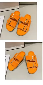 Detail shot of vibrant orange canvas sandals with frayed edges and double buckles.