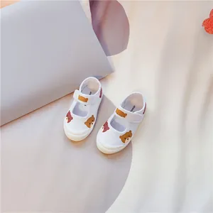 Detailansicht weißer Kinder-Segeltuchschuhe mit süßen Bärenmustern und Klettverschlüssen.