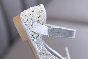 Primer plano de zapatos de princesa con purpurina plateada, pedrería y perlas para niña.