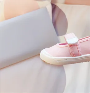 Detaillierte Nahaufnahme eines rosa Leinenschuhs für Kinder mit weißer Kappe und Klett.