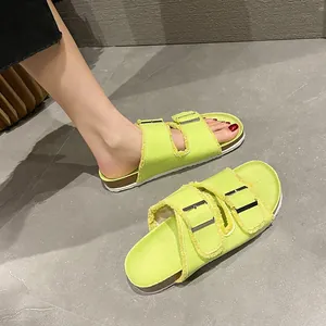 Vibrant lime green canvas slide sandals with fringe buckles and flat soles.