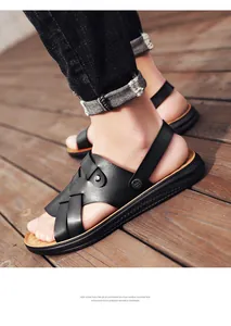 Close-up of black leather sandals with crisscross straps on a rustic wooden deck