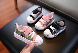 Close-up view of color-blocked children's canvas shoes with Velcro straps and daisy detail.