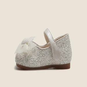 Vista lateral de zapatos de princesa con purpurina plateada y flor de perlas blancas.