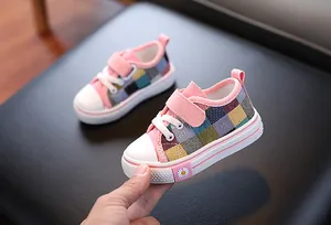 Detail view of pink plaid children's canvas shoes with daisy pattern on rubber sole