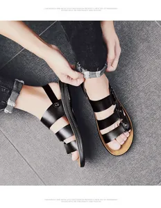 Close-up of stylish black leather men's sandals featuring a three-strap design on a grey tile floor