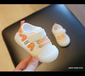 Nahaufnahme von weißen, atmungsaktiven Mesh-Babyschuhen mit orangen Akzenten