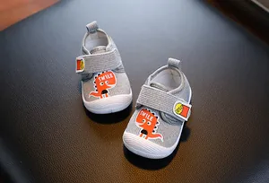 Chaussures de marche grises pour bébé avec un dinosaure mignon et semelles souples.