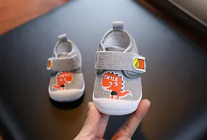 Gros plan de chaussures de marche pour bébé grises avec dinosaure et texte SMILE
