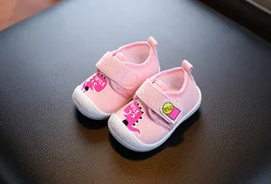 Gros plan de chaussures de marche roses pour bébé avec dinosaure et semelle souple