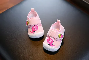 Détail de chaussures bébé roses avec dinosaure mignon et semelles souples