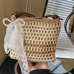 Primer plano de un bolso de hombro tejido con lazo de encaje blanco y detalles de perlas