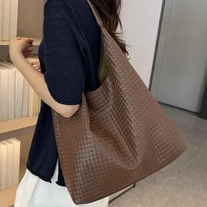 Bolso hobo marrón con diseño trenzado llevado por una modelo en un interior elegante