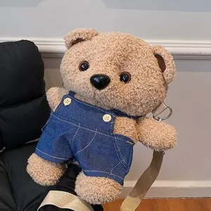 Vista detallada de un bolso bandolera de oso de peluche marrón con peto vaquero.
